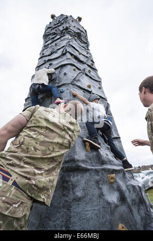 Worcester, Worcestershire, Regno Unito. 16 Ago, 2014. La seconda guerra mondiale e armi contemporaneo ha dato il saluto a Worcester Racecourse come uno dei punti salienti dell'Artiglieria giorno speciale, che segna il centocinquantesimo anniversario della città esercito locale unità di riserva, 214 (Worcestershire) Batteria Royal Artillery e il centenario della Grande Guerra. Nella foto: Bambini arrampicarsi arrampicata su una colonna installata su Worcester Racecourse come parte della città è giorno di artiglieria. © Lee Thomas/ZUMA filo/Alamy Live News Foto Stock