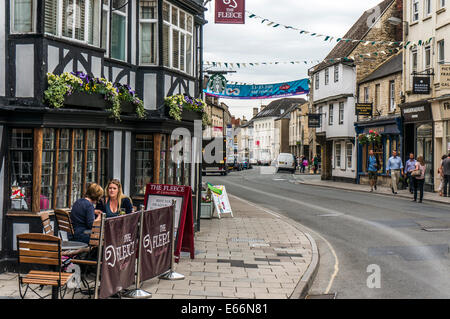 Centro città vista con due signore avente un pasto al di fuori di un ristorante, Cirencester, Cotswolds, Gloucestershire, Inghilterra, Regno Unito. Foto Stock