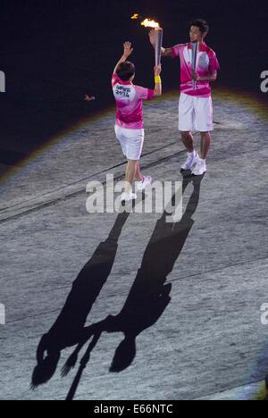 Nanjing. 16 Ago, 2014. Nuotatore cinese Tang Yi riceve la fiamma dal cinese ping-pong player Zhang Jike alla cerimonia di apertura della Nanjing 2014 Olimpiadi della Gioventù in Nanjing, a est della capitale cinese della provincia di Jiangsu. Credito: Chen Cheng/Xinhua/Alamy Live News Foto Stock