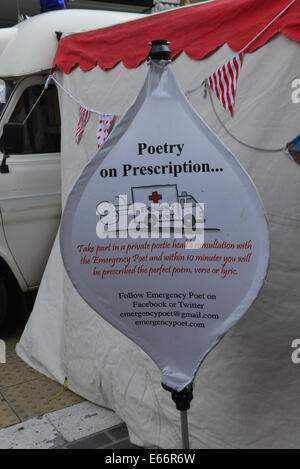 Seven Dials, Londra, Regno Unito. Il 16 agosto 2014. Un "Emergenza Poeta' fornisce prescrizioni. Il Seven Dials è priva di traffico e la copertura in erba artificiale come le persone godono di festival. Credito: Matteo Chattle/Alamy Live News Foto Stock