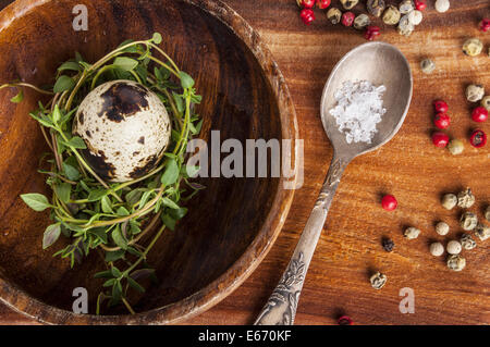 Uovo di quaglia e timo su uno sfondo di legno Foto Stock