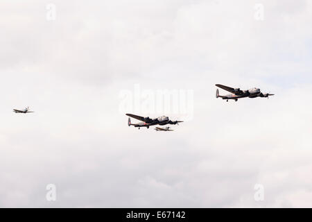 Kent, Regno Unito. 16 Ago, 2014. Un fly-over dal solo due navigabilità Avro Lancaster bombardieri a sinistra da WW2 in formazione con due Spitfires alla sesta annuale combinati Ops mostra a Headcorn Airfield. Dotato di fly-overs, guerra rievocazioni, Fancy Dress, effettivo e memorabilia di replica e di più. Credito: Tom Arne Hanslien/Alamy Live News Foto Stock