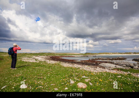 Osservazione degli uccelli guardando attraverso il binocolo per guardare gli uccelli sulla costa di Traigh Iar beach Balranald riserva RSPB North Uist Scotland Regno Unito Foto Stock