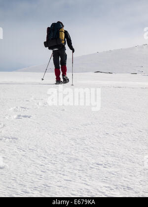 Uomo con zaino pesante con le racchette da neve in inverno il paesaggio di montagna. Huldraheimen, Gausdal Westfjel, Norvegia Foto Stock