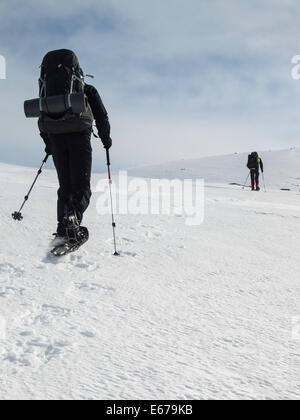 Due uomini con zaini pesanti con le racchette da neve in inverno il paesaggio di montagna. Huldraheimen, Gausdal Westfjel, Norvegia Foto Stock