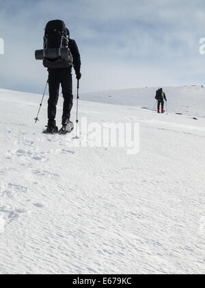 Due uomini con zaini pesanti con le racchette da neve in inverno il paesaggio di montagna. Huldraheimen, Gausdal Westfjel, Norvegia Foto Stock