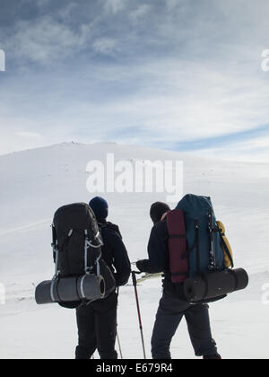 Due uomini con zaini pesanti mappa di lettura in montagna in inverno il paesaggio. Huldraheimen, Gausdal Westfjel, Norvegia Foto Stock