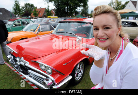 Rastede, Germania. 17 Ago, 2014. Sonja in 50s dress presenta la siamo auto Dodge Coronet dal 1959 all'ottavo vintage car meeting per automobili e motociclette in Rastede, Germania, 17 agosto 2014. Foto: Ingo Wagner/dpa/Alamy Live News Foto Stock