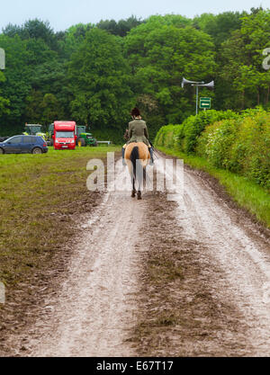 Staffordshire County Show, Inghilterra, 2014. La donna a cavallo verso van per cavalli sul bagnato via fangoso dopo heavy rain. Foto Stock