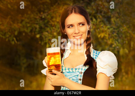 Giovane donna bavarese tenendo premuto il boccale di birra Foto Stock