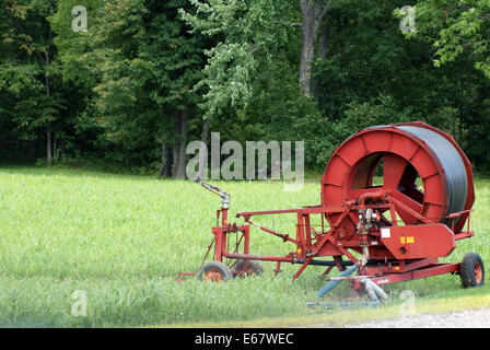 Settore Apparecchiature per irrigazione si siede sul bordo di una lussureggiante campo, pronti per irrigare le colture Foto Stock