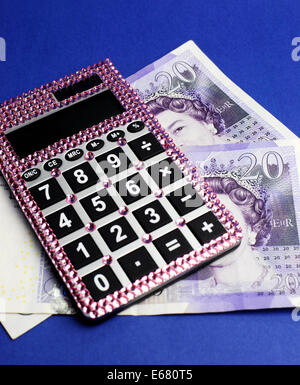 Due inglese Bank of England venti Pound note su sfondo blu con rosa bling calcolatrice. Verticale. Foto Stock