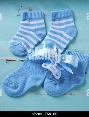 Baby boy vivaio blu e calzini bianchi e il succhietto, su aqua vintage shabby chic di sfondo Foto Stock