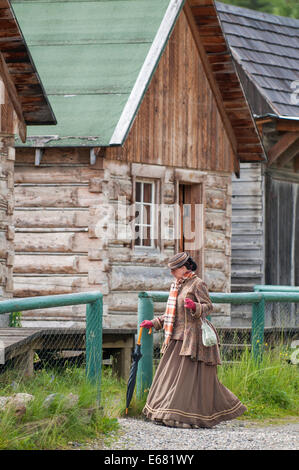 La donna nel periodo dress baite e gli edifici lungo la strada principale storica Vecchia città d'oro Barkerville, British Columbia, Canada. Foto Stock