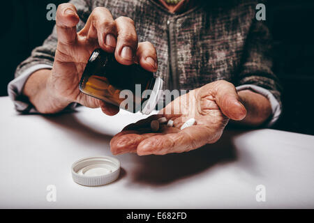 Vista ritagliata della donna anziana tenendo la prescrizione di medicinali da pillola bottiglia. Femmina Senior le mani di pillole di versamento sul suo palm whi Foto Stock