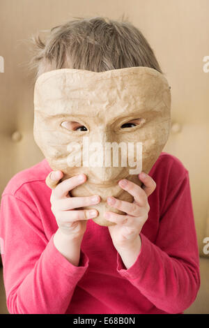 Triste bambina nascondendo la faccia dietro la maschera di felice Foto Stock