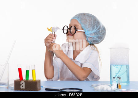 Farmacia ragazza seduta al tavolo con i reagenti per la chimica classe e mette gli esperimenti Foto Stock
