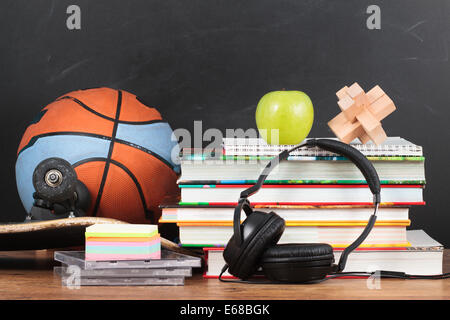 Accessori per la scuola su desktop con la lavagna in background Foto Stock