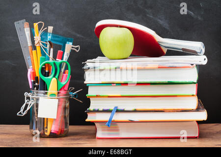 Accessori per la scuola su desktop con la lavagna in background Foto Stock