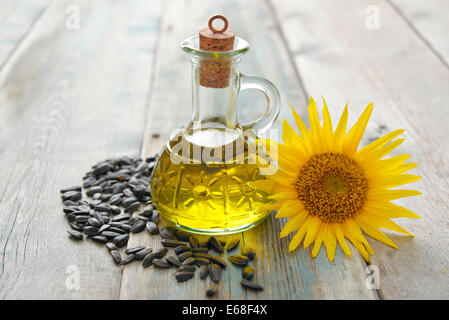 Olio di semi di girasole in bottiglie con semi e fiore su sfondo di legno Foto Stock