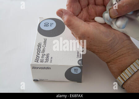 Donna anziana con livelli di colesterolo elevati premendo statina tablet in mano dalla confezione in blister Foto Stock