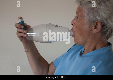 Anziana donna asmatica utilizzando un distanziatore Volumatic dispositivo per Ventolin inalazione Foto Stock