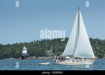 Isola di Fox Thorofare, ME - 11 agosto 2014. Sloop Loon passando Goose Rocks luce. La luce è di proprietà di conservazione del faro a luce rotante. Foto Stock