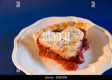 Una fetta di fatto in casa torta di ciliegie su una piastra bianca, sfondo blu. Stati Uniti d'America Foto Stock