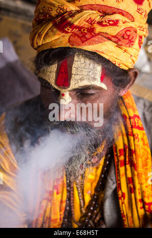 Un sadhu indù (uomo santo) fumando un hash tubo (chillum) presso il Tempio Hindu di Pashupatinath, a Kathmandu, Nepal. Foto Stock