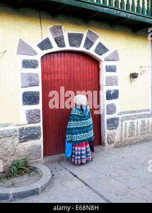 Local donna in abiti tradizionali di entrare in una porta - Chivay, Perù Foto Stock