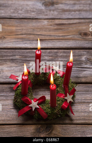 Natale con sfondo rosso quattro candele accese. Foto Stock