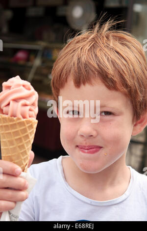 Cinque anni di vecchio ragazzo tenendo una fragola gelato in un cono Foto Stock