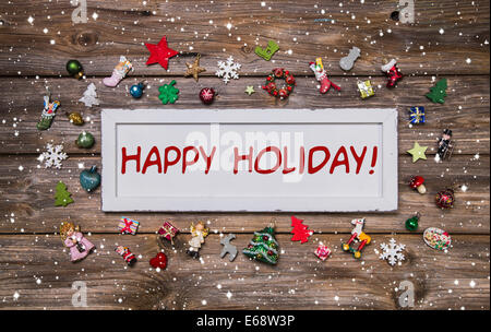 Happy Holiday - Natale elogiativo carta in diversi colori su sfondo di legno. Foto Stock