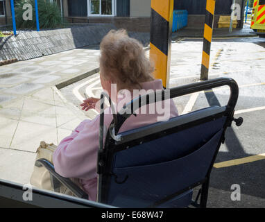 Anziani paziente femmina in ospedale carrozzella fumare vicino a Baia di ambulanza al di fuori del NHS hospital, England, Regno Unito Foto Stock