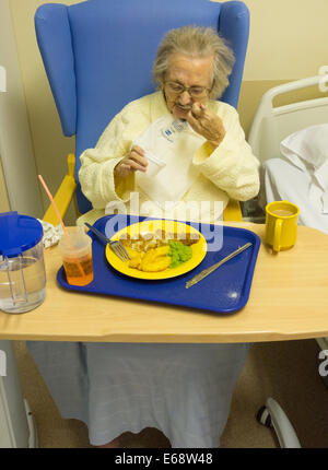 Paziente anziano nel suo degli anni novanta a mangiare pesce e patatine in ospedale NHS in Inghilterra, Regno Unito Foto Stock