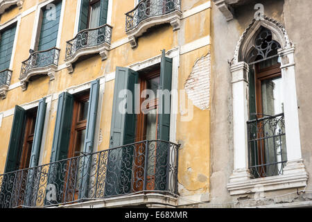 Dettaglio del piano superiore della vecchia casa con balcone, porte Francesi, persiane verdi e stacca il gesso. Foto Stock