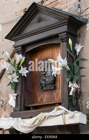 Santuario di un Santo e Cristo Bambino adornata con gigli di Pasqua su e la vecchia casa in Venezia. Foto Stock