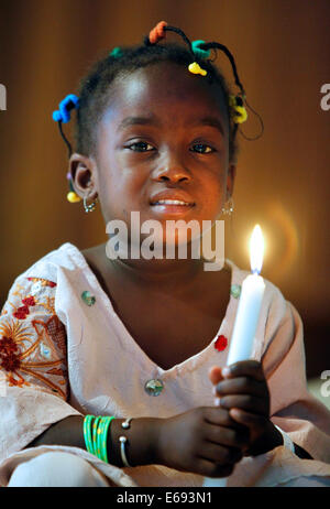 La ragazza (3 anni) tenendo la candela in una chiesa cattolica a Kaolack, Senegal Africa Foto Stock