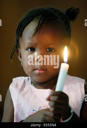 La ragazza (2 anni) tenendo la candela in una chiesa cattolica a Kaolack, Senegal Africa Foto Stock