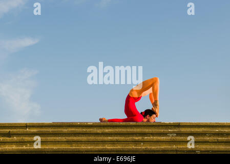 Giovane donna pratica di Hatha yoga, all'aperto, che mostra la posa poorna Shalabhasana, piena Locust Foto Stock