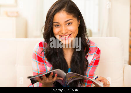 Donna ispanica rivista di lettura sul divano Foto Stock