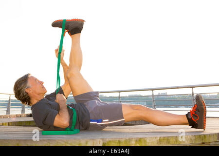 Uomo caucasico stretching in waterfront park Foto Stock