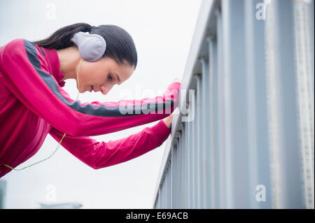 La donna caucasica ringhiera di contenimento, ascoltando le cuffie Foto Stock