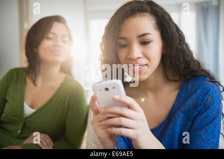 Madre guarda la figlia uso telefono cellulare Foto Stock