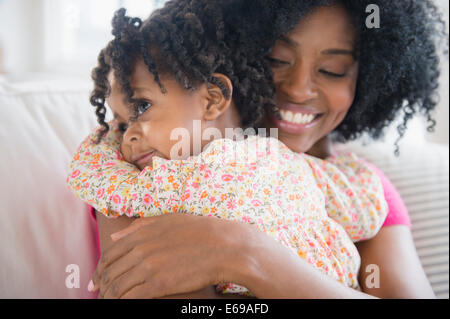 La madre abbraccia la figlia sul divano Foto Stock