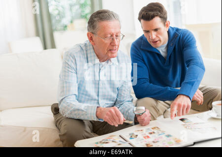 Caucasian padre e figlio esaminando raccolta di francobolli Foto Stock