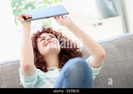 Donna ispanica con tavoletta digitale sul divano Foto Stock