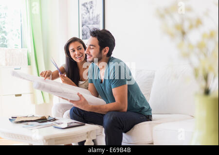 Giovane esaminando le cianografie nel soggiorno Foto Stock