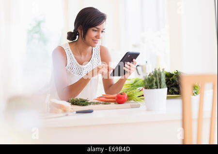 Donna ispanica cucinare con tavoletta digitale Foto Stock