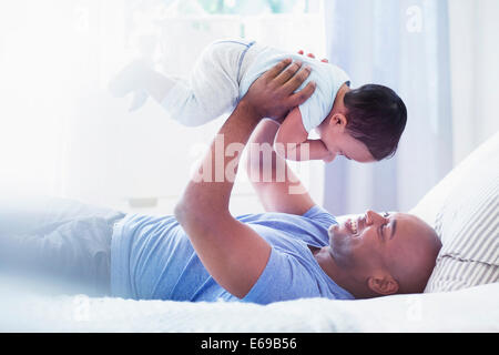 Padre giocando con il bambino sul letto Foto Stock